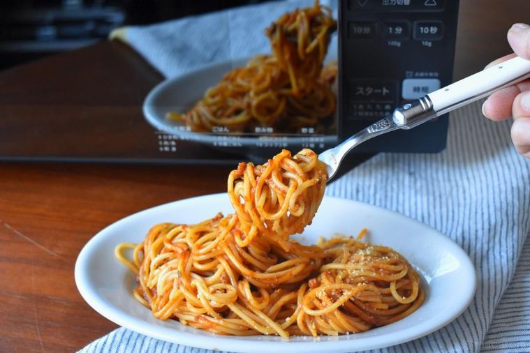 電子レンジの前に置いたミートソースパスタ