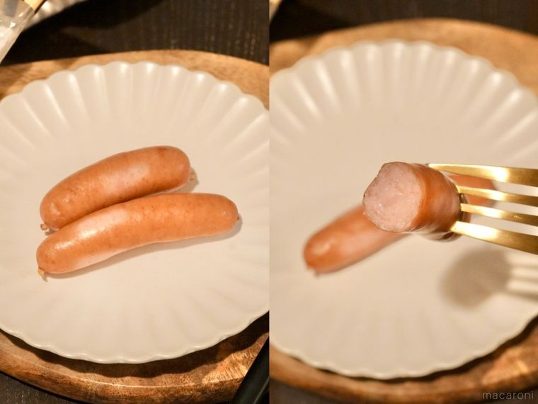 木のカッティングボードと白い皿にのったゆでたウインナーソーセージよ金のフォーク