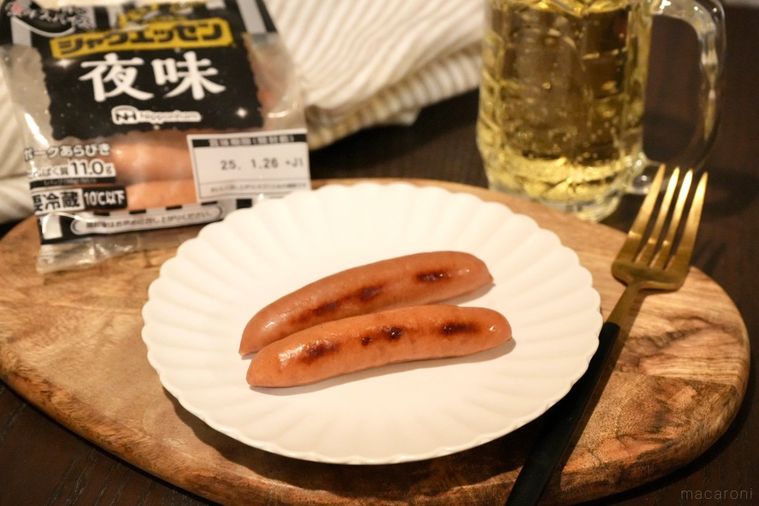 木のカッティングボードと白い皿にのった夜味のウインナーソーセージとパッケージとジョッキ