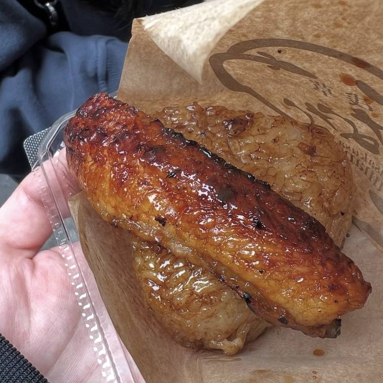 食べ歩き用の紙に包まれた、しょうゆダレの染みたおにぎりと鰻