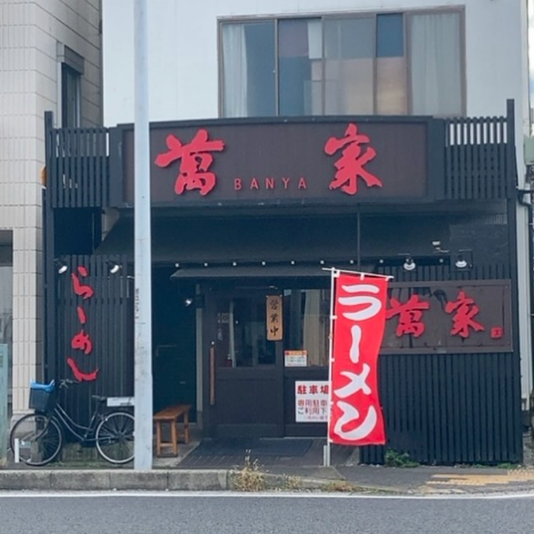 赤い看板と黒い外壁が目立つらーめん萬家の外観