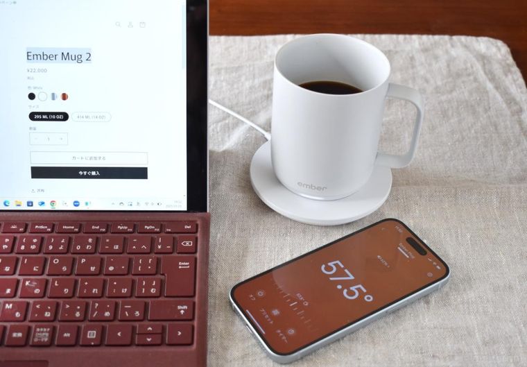 PCの横に置いたマグカップとスマートフォン