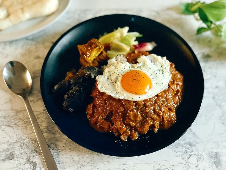 ツルヤのキーマカレーを野菜と一緒に皿に盛り付け、目玉焼きをトッピングしたところ