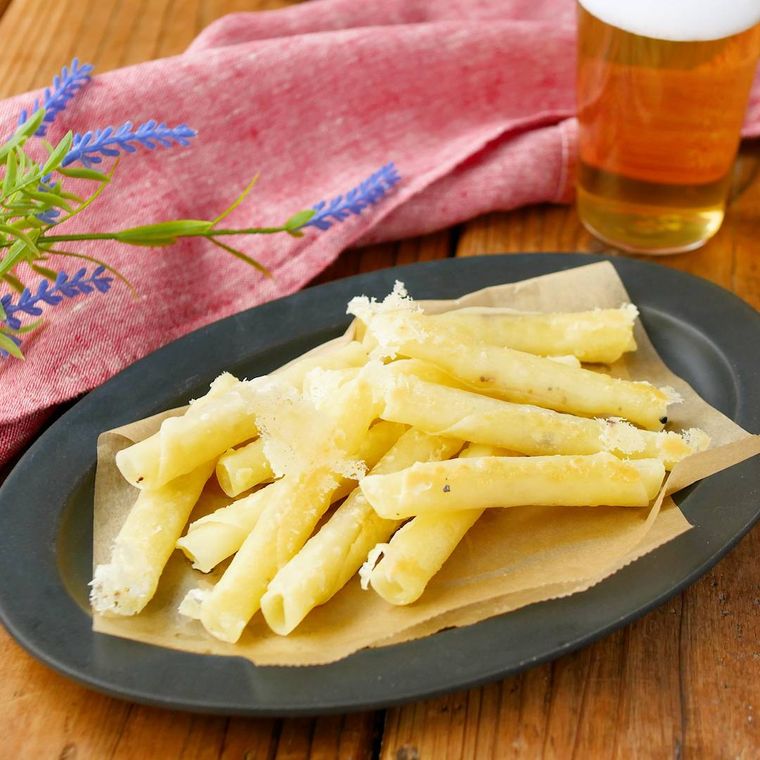 黒い楕円形の皿に盛り付けた餃子の皮のチーズスティック