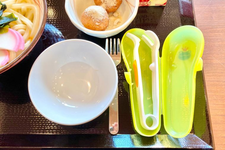黒いお盆にのった子ども用食器とフォークとうどんカッター