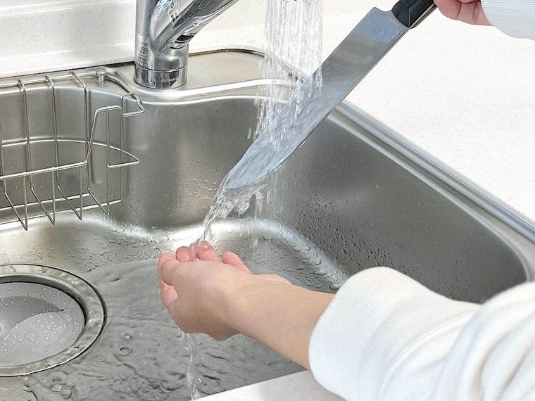 包丁から流れ落ちる水で手を洗っている様子