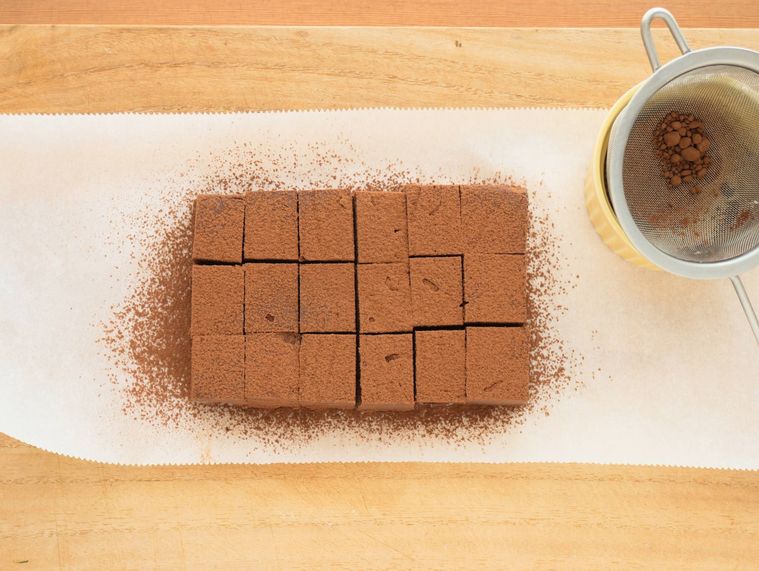 カットした生チョコに純ココアパウダーを振りかける様子