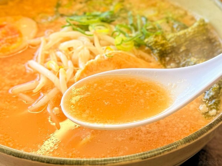「にんにくたまごラーメン」のスープをレンゲですくっている様子