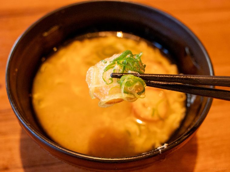 みそ汁に入っている麩と青ねぎを箸で持ち上げている様子