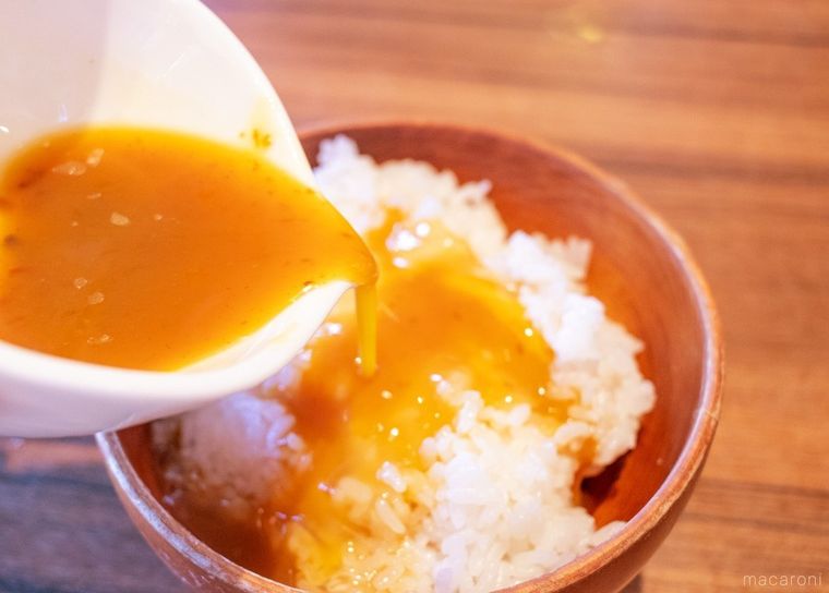 オリジナルソースを混ぜた生卵をご飯に掛けている様子