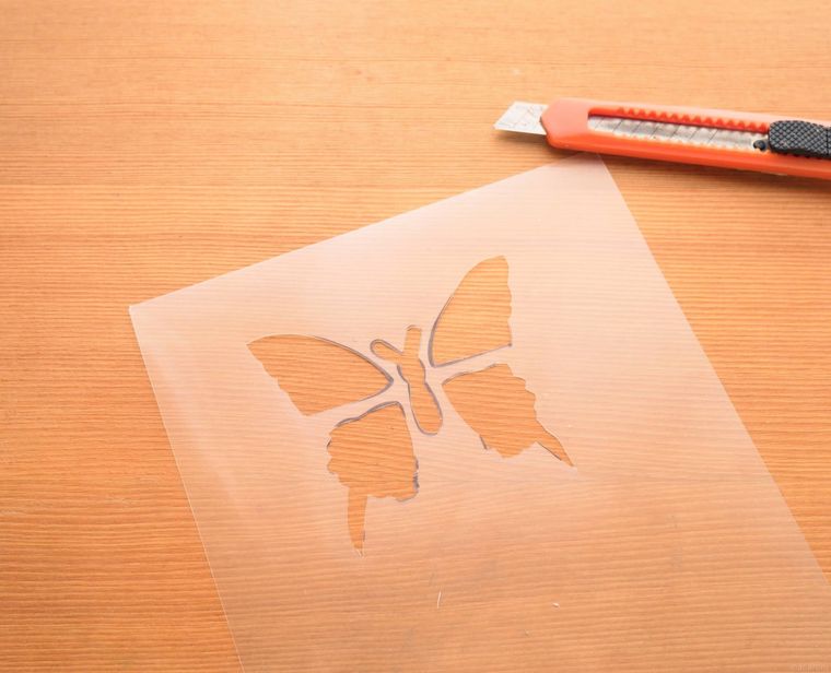 蝶の形に切り取ったクリアファイルとカッター