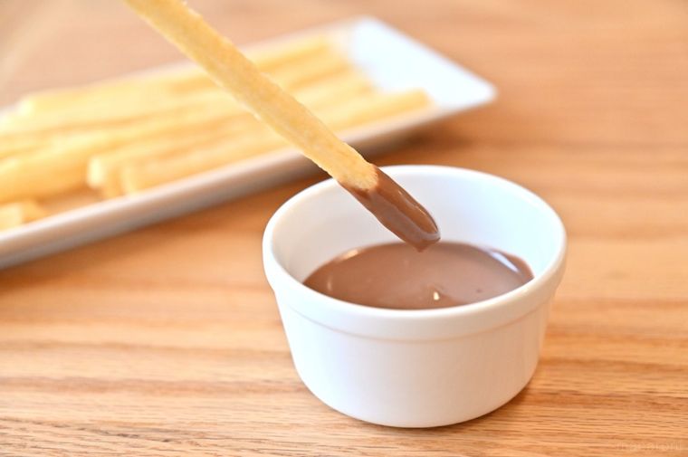 ココットに入ったチョコレートに棒状スナックをディップしている