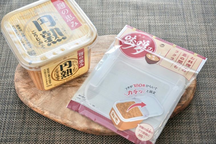 木のカッティングボードにのった味噌用のふたとパッケージ