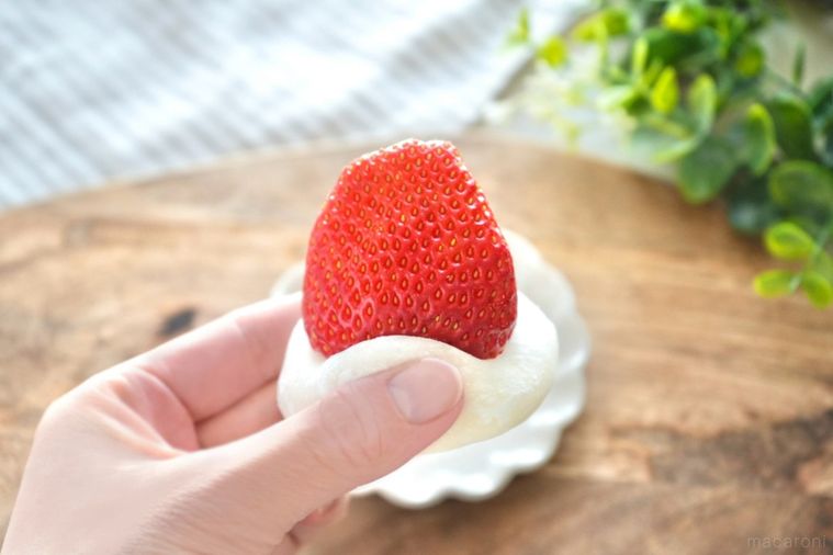 木のカッティングボードと白い小皿といちごののった生雪見だいふくとストライプの布とグリーン