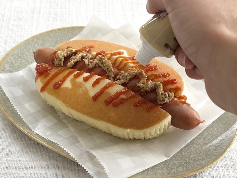 ホクチーケーキドッグにマスタードをかけている様子