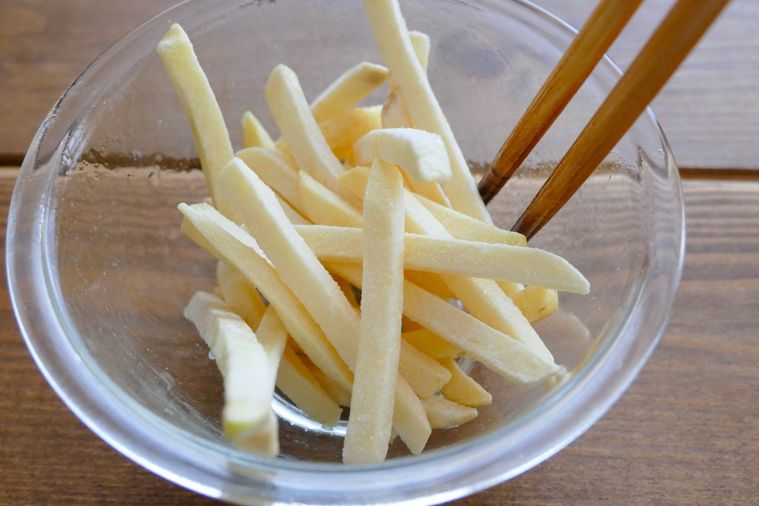 冷凍ポテトにサラダ油を加えて箸で和える様子