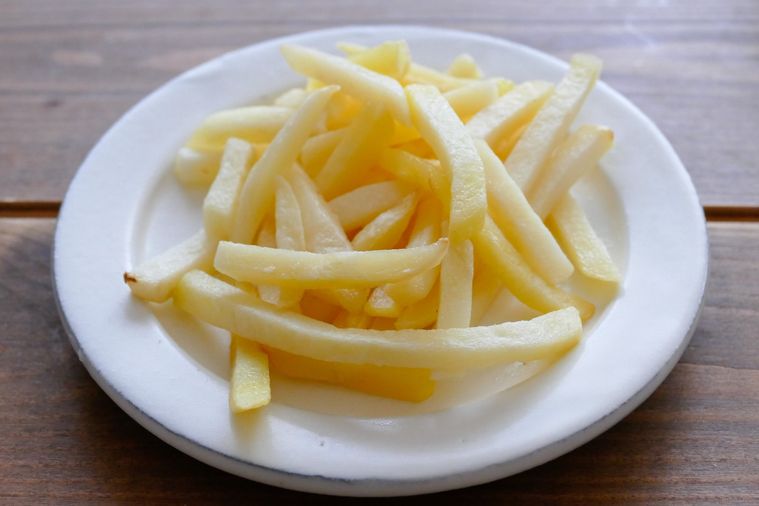 電子レンジで加熱したポテトが盛られている白い皿