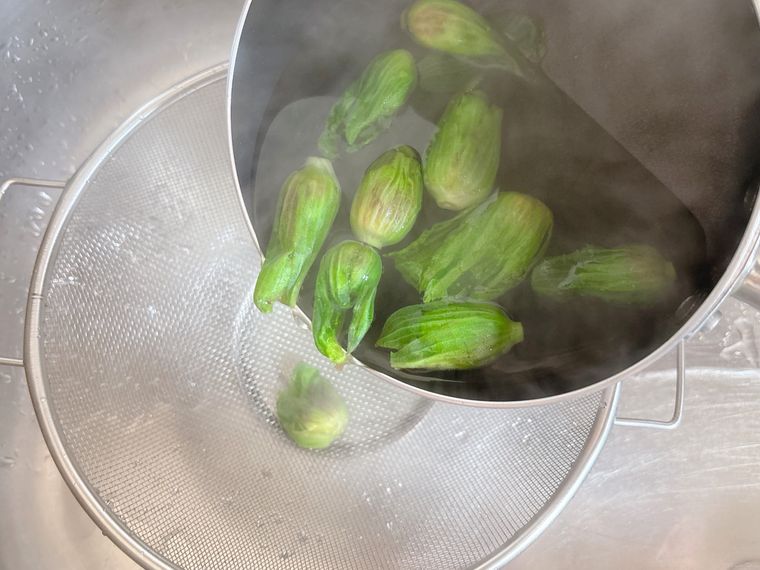 ゆでたふきのとうをザルにあげる様子