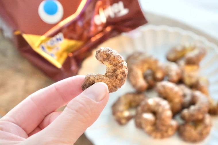 木のカッティングボードと白い皿にのったショコラ味のキャラメルコーンを手に持つ様子