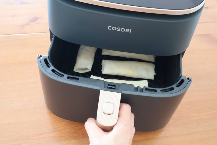 ノンフライヤーに春巻きを入れている