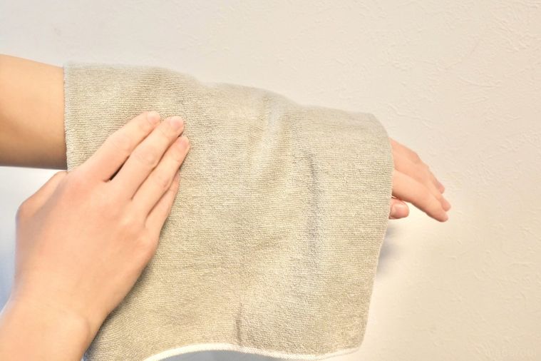 グレーのタオルで腕を拭く様子