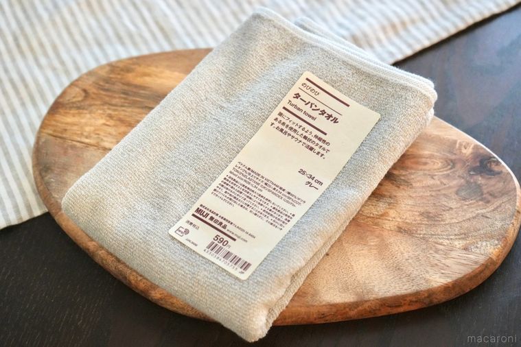 木のカッティングボードにのったグレーのタオル地のヘアターバンとストライプの布