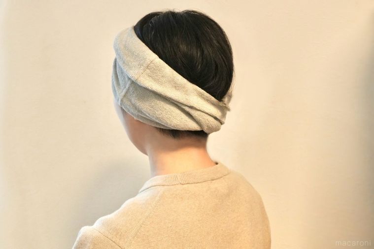 グレーのタオル地のヘアターバンをヘアバンドとしてねじって頭につける様子