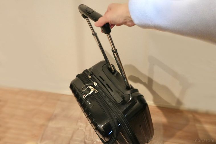 黒いスーツケースを手で引く様子