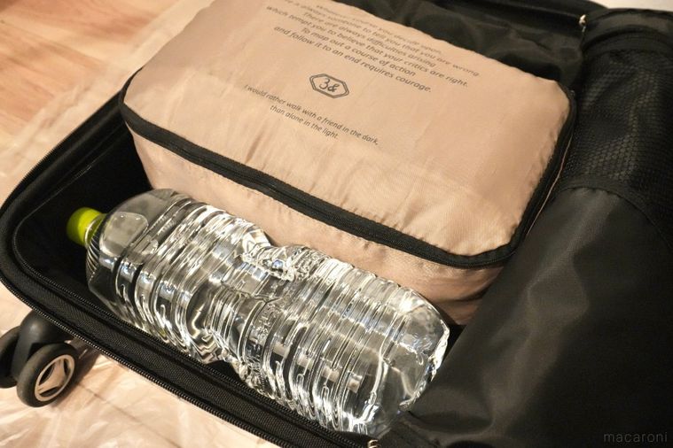 黒いスーツケースに水のペットボトルと衣類ポーチをパッキングした様子