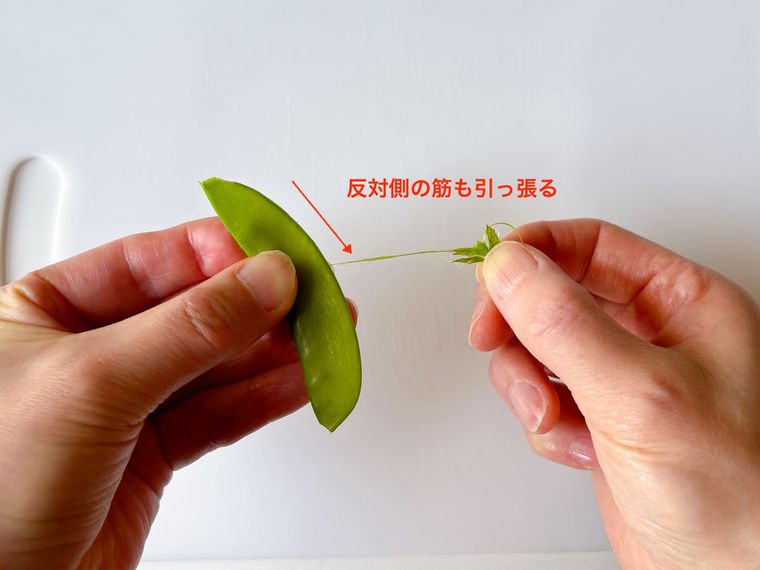 さやえんどうの筋を下向きに引っ張る様子