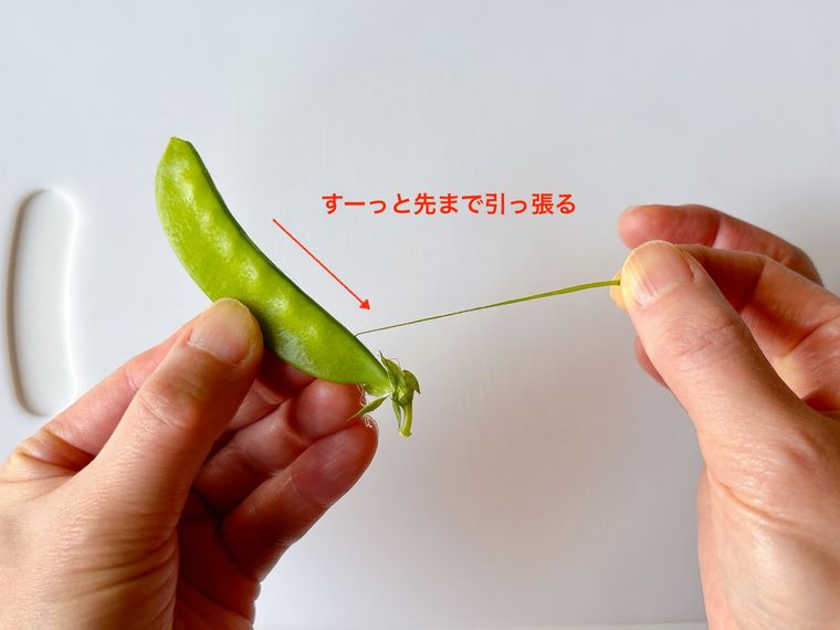 さやえんどうの筋を先端まで引っ張る様子