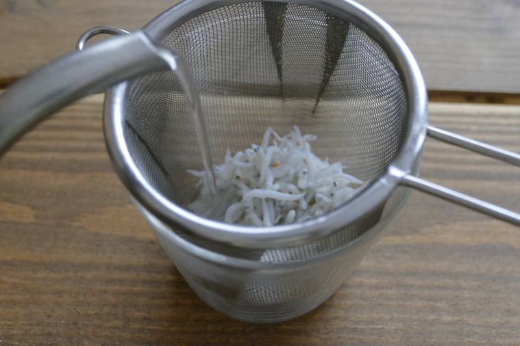 茶こしに入れたしらすに熱湯を注ぐ様子