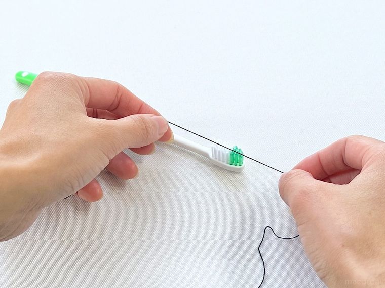 歯ブラシの上に糸をのせている様子