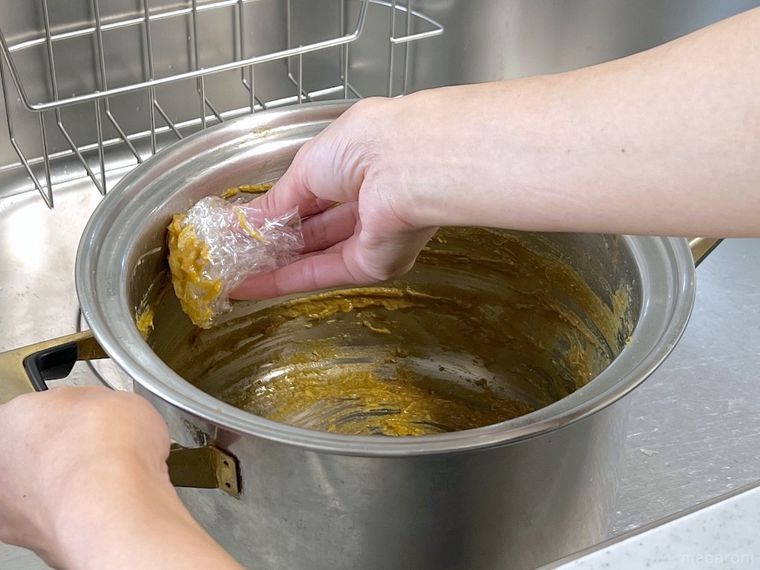 鍋に残ったカレーをラップで拭き取っているところ