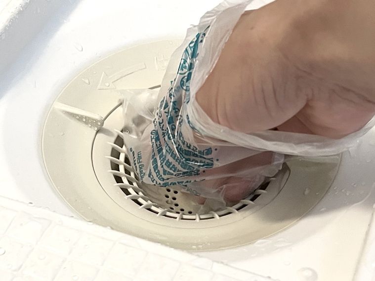 開いた梱包材で排水口のゴミを取っているところ