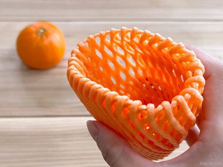 オレンジ色のフルーツネットを手で持っている様子