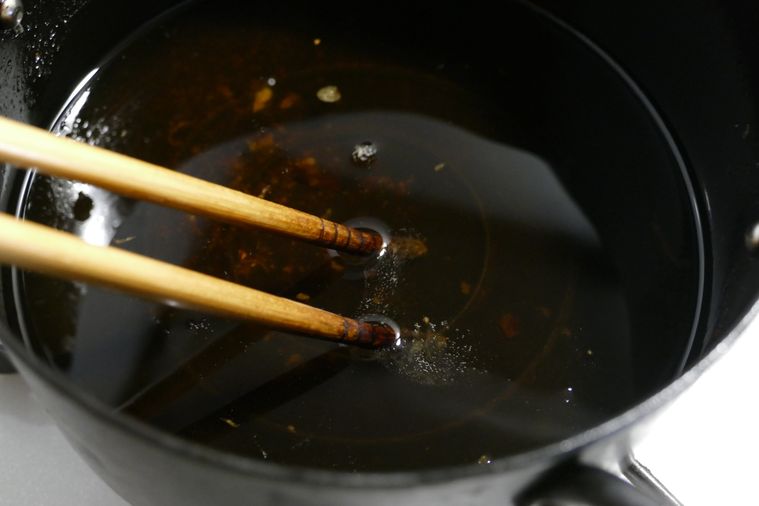 揚げ油に菜箸を入れて温度を確認する様子