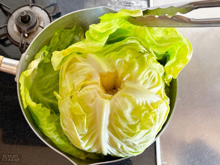 ゆでたキャベツの葉をトングで取る様子