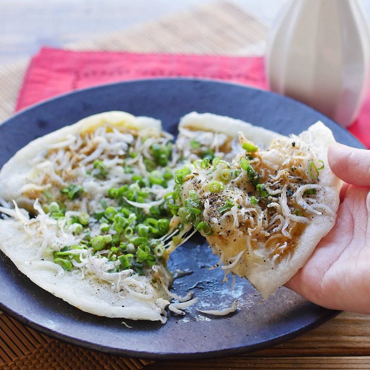 黒い丸皿に盛り付けたしらすとねぎのおもちピザ