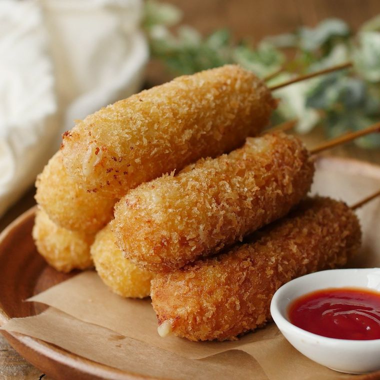 ワックスペーパーにのせた串に刺したソーセージコロッケ