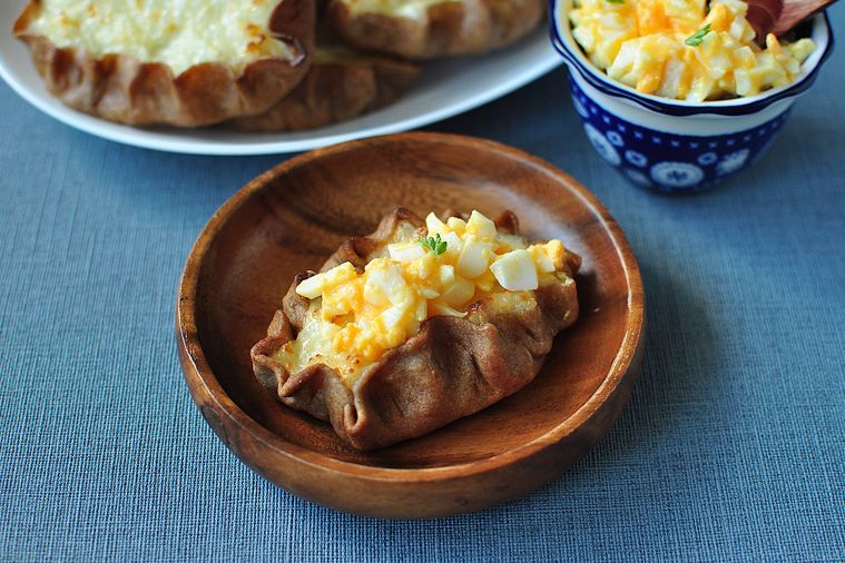 ムナボイをのせたカルヤランピーラッカが木の皿に盛り付けてある