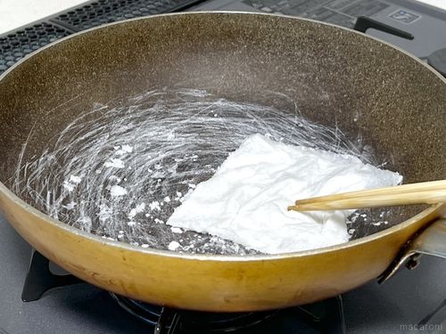 塩が入ったフライパンをキッチンペーパーでこすっている様子
