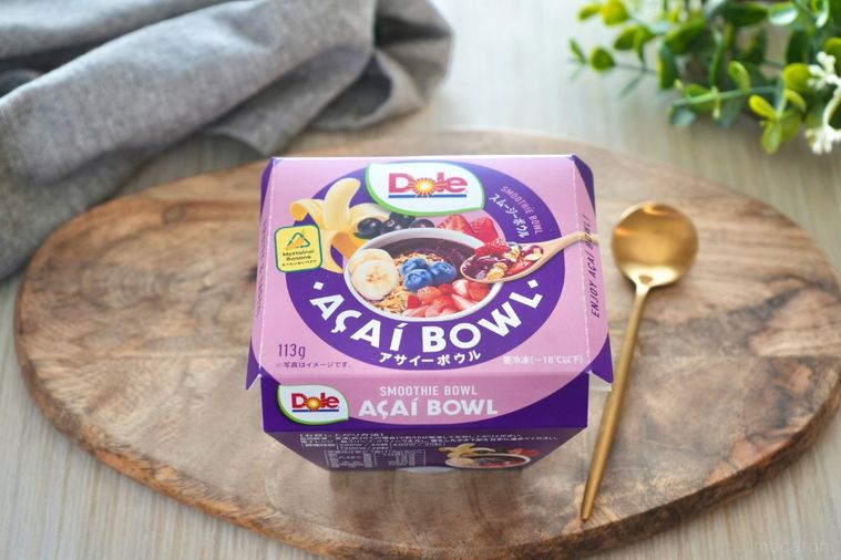 木のカッティングボードにのったアサイーボウルと金のスプーンとグリーンとグレーの布