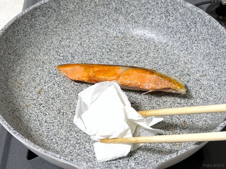 鮭から出てきた脂をキッチンペーパーで拭き取っている様子