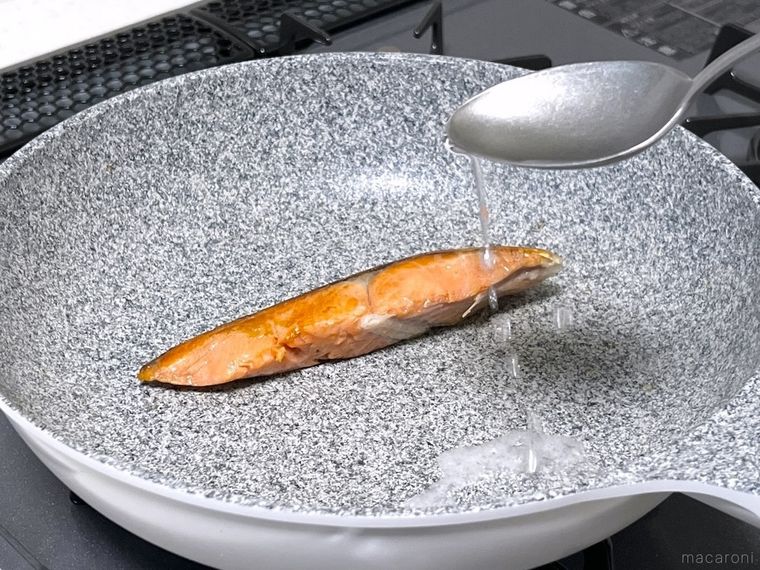 鮭が入ったフライパンに酒を加えている様子