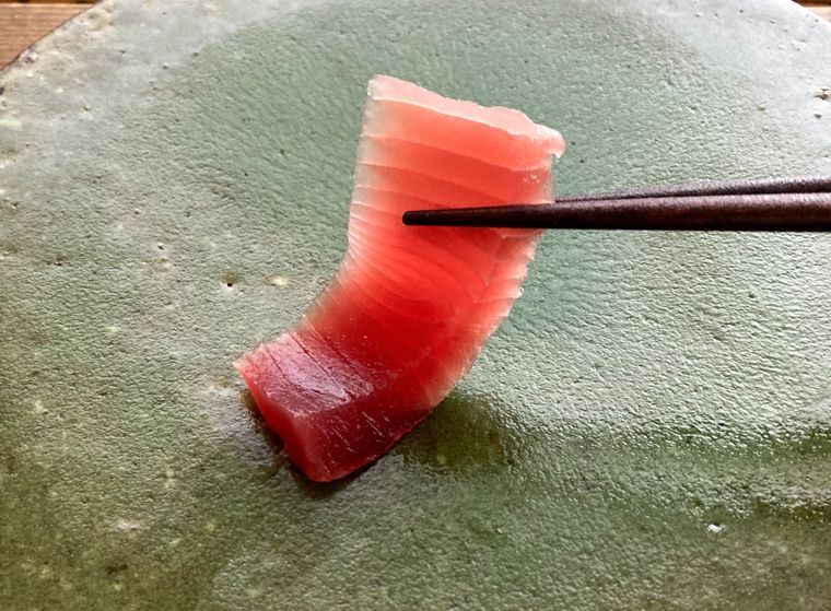 塩水で洗ったまぐろを箸で持ち上げる様子