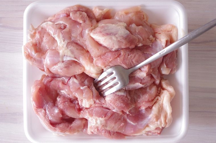 鶏もも肉にフォークで穴を開ける様子