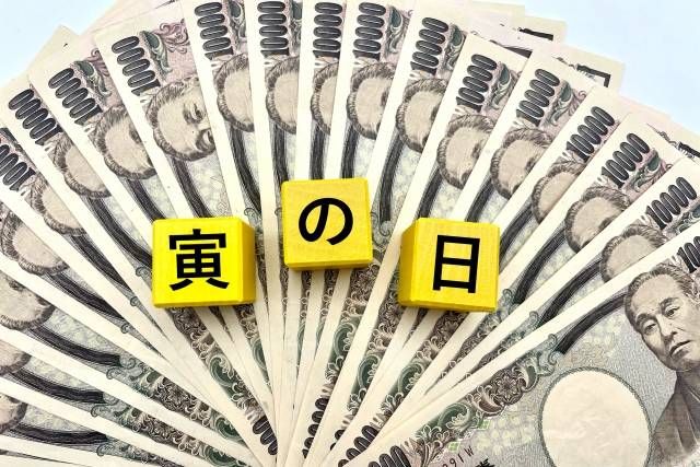 一万円札の上に寅の日と書かれたブロックが置かれている