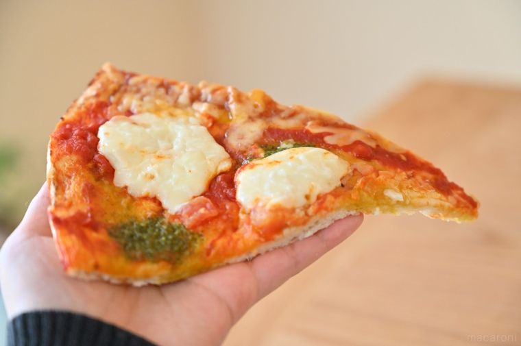 手のひらにのせたMEGAサイズのマルゲリータピザひと切れ