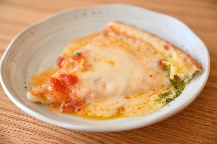 お皿にチーズが流れているひと切れのピザ